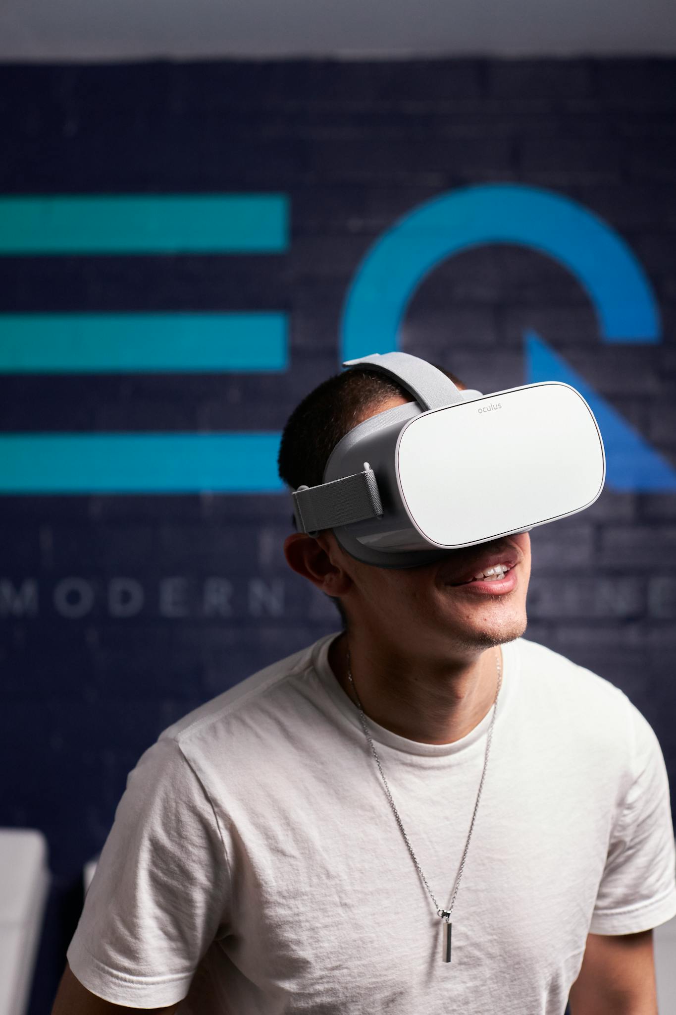 A man wearing VR goggles smiles while engaging with virtual reality technology indoors.
