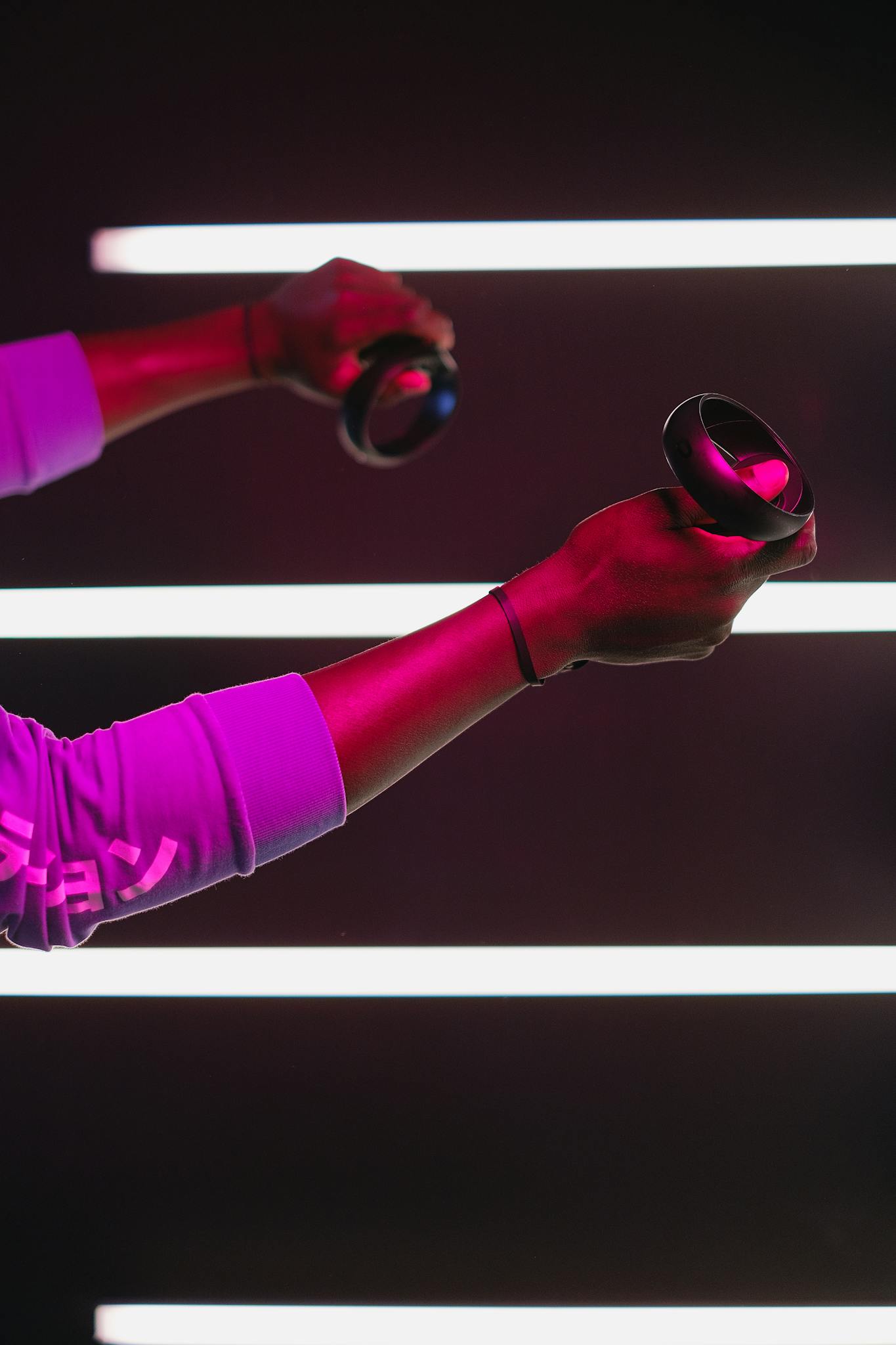 Close-up of an adult using VR controllers with neon lights creating a dynamic gaming atmosphere.