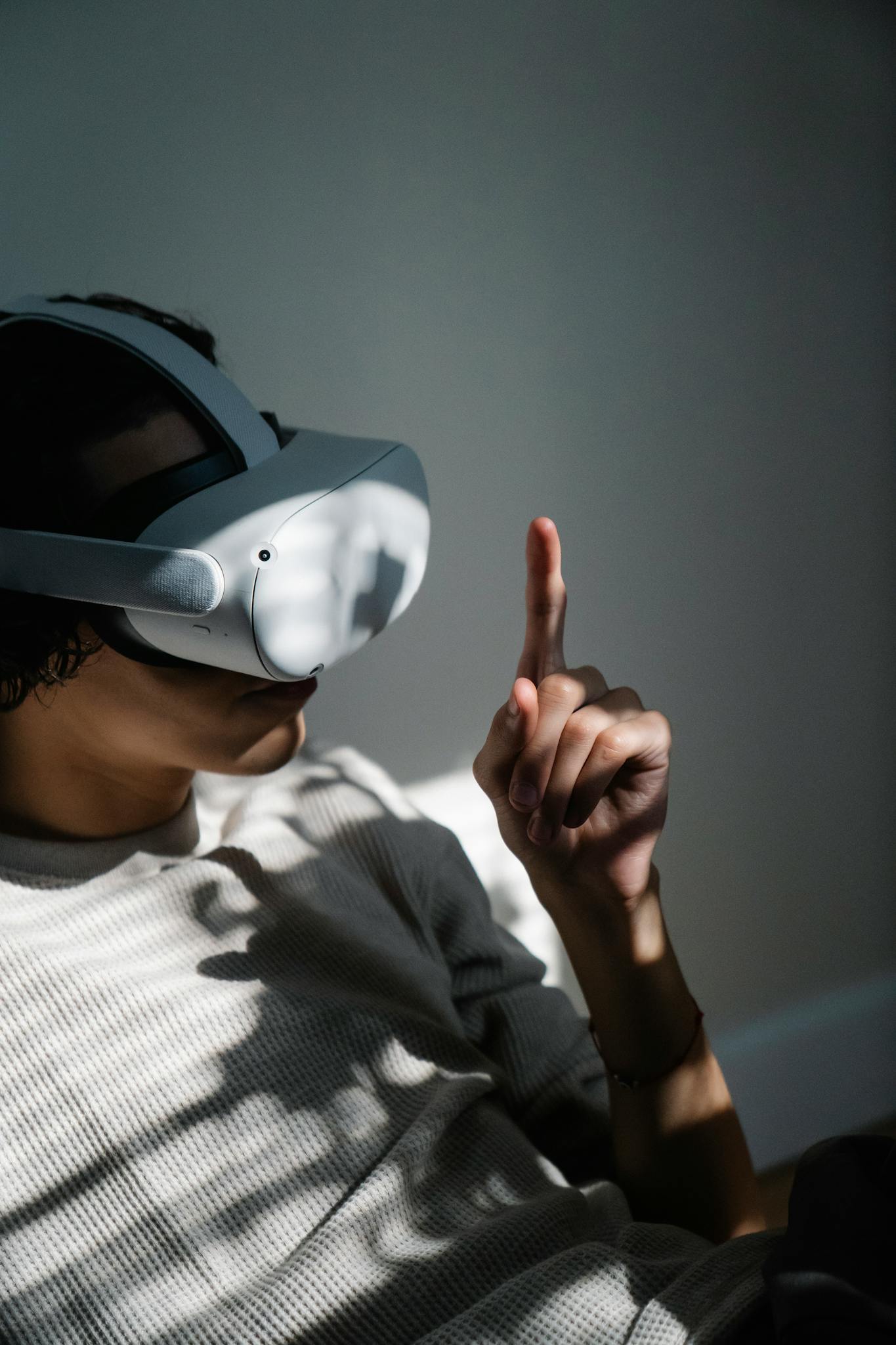Young man using VR headset indoors, engaging with virtual reality in a modern setting.